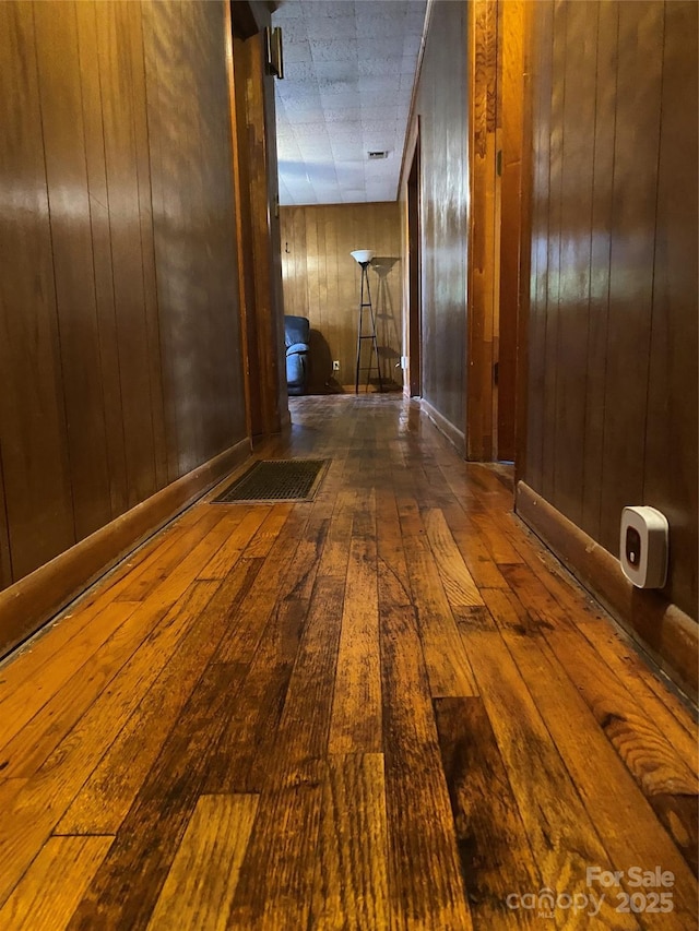 hall with dark hardwood / wood-style floors and wooden walls