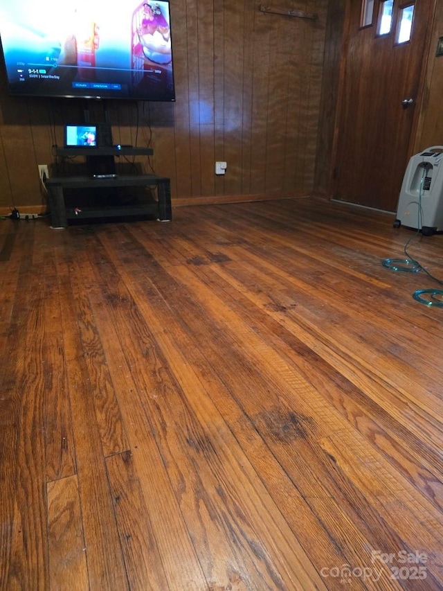 unfurnished living room with hardwood / wood-style flooring and wood walls