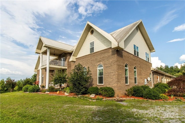 view of side of home featuring a balcony and a yard