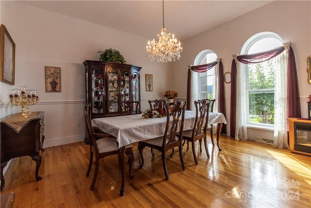 dining space featuring a notable chandelier, lofted ceiling, and light hardwood / wood-style flooring