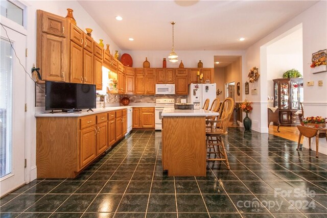 kitchen with white appliances, a kitchen breakfast bar, tasteful backsplash, decorative light fixtures, and a center island