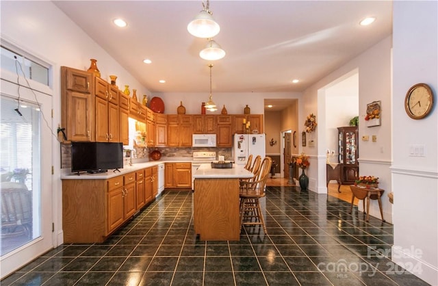 kitchen featuring a breakfast bar area, a center island, pendant lighting, backsplash, and white appliances