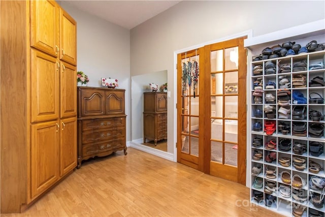 walk in closet with light hardwood / wood-style flooring and french doors