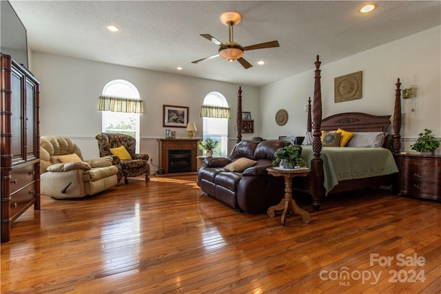 bedroom with hardwood / wood-style floors, ceiling fan, and a textured ceiling