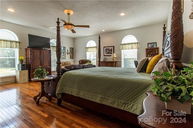 bedroom with ceiling fan, a textured ceiling, hardwood / wood-style flooring, and multiple windows