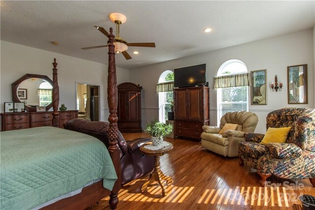 bedroom with multiple windows, dark wood-type flooring, and ceiling fan