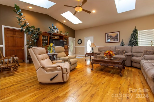 living room with light hardwood / wood-style flooring, ceiling fan, and vaulted ceiling with skylight