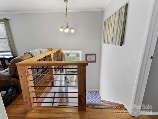 staircase featuring an inviting chandelier, ornamental molding, and wood-type flooring