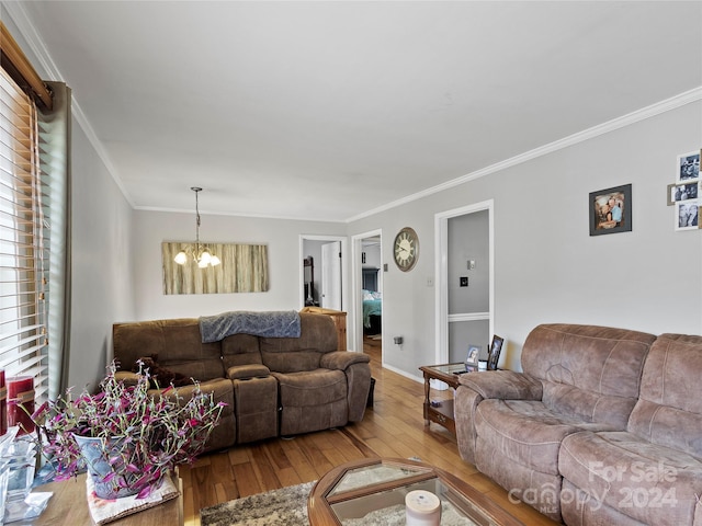 living room featuring crown molding, a chandelier, and light wood-type flooring