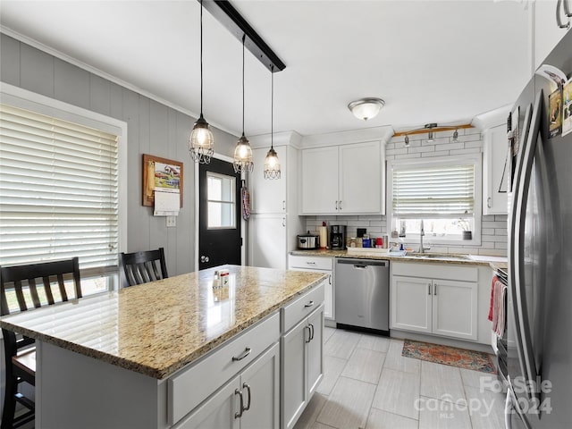 kitchen featuring appliances with stainless steel finishes, white cabinets, sink, a center island, and hanging light fixtures