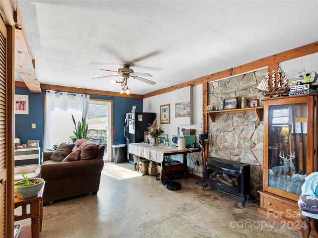 living room with ceiling fan, a wood stove, a fireplace, and a textured ceiling