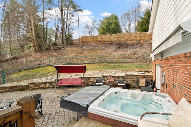 deck with an outdoor hot tub and a patio area