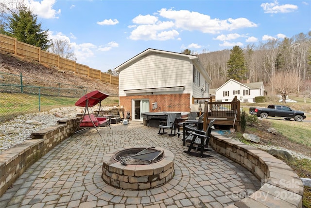 view of patio / terrace with an outdoor fire pit, a deck, and a fenced backyard