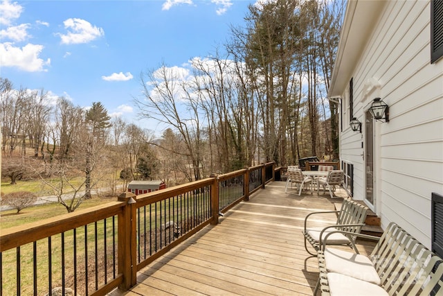 deck featuring outdoor dining area and a lawn