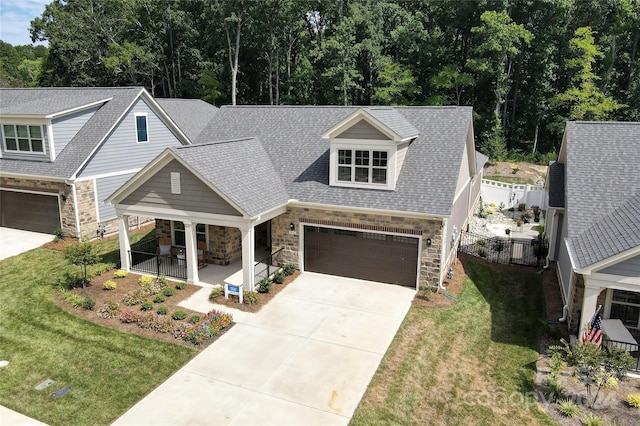 view of front of home featuring a front yard, covered porch, and a garage