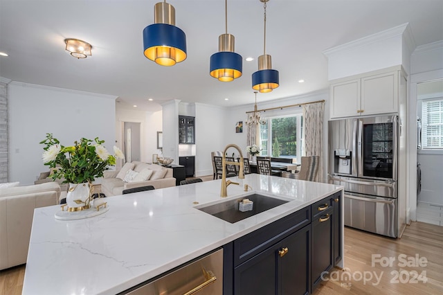 kitchen with pendant lighting, sink, stainless steel fridge, a wealth of natural light, and light stone counters