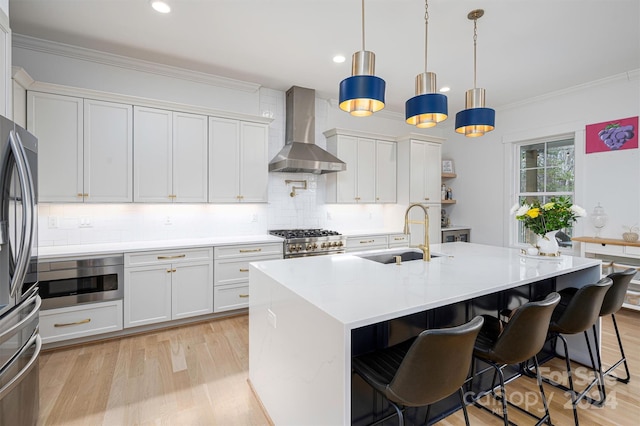 kitchen featuring white cabinetry, hanging light fixtures, stainless steel appliances, and wall chimney range hood