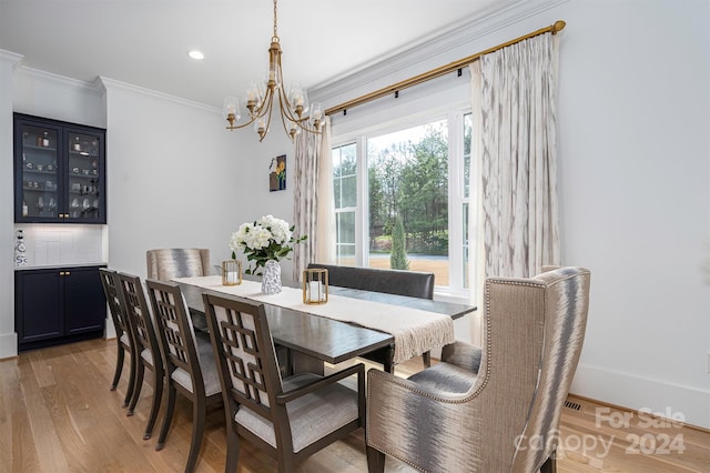 dining space with a notable chandelier, crown molding, and light hardwood / wood-style flooring