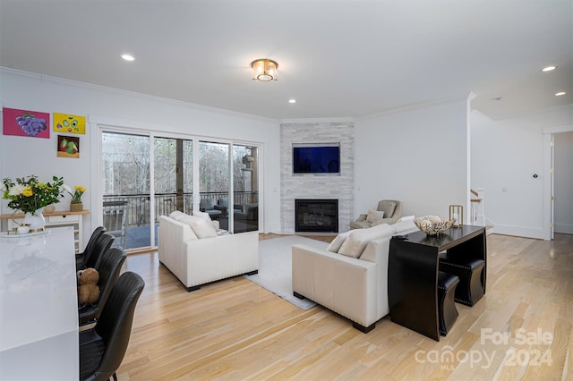 living room featuring a stone fireplace, light hardwood / wood-style flooring, and ornamental molding