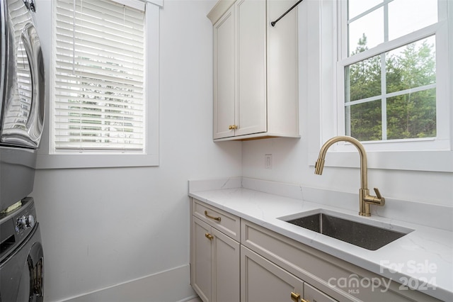 kitchen with stacked washer and dryer, plenty of natural light, and sink