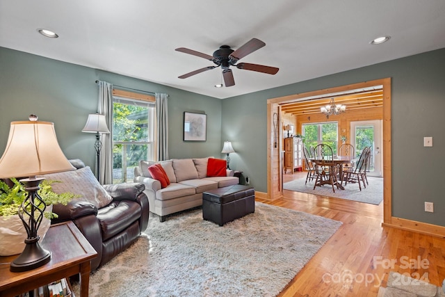 living room with a healthy amount of sunlight, ceiling fan with notable chandelier, and hardwood / wood-style flooring