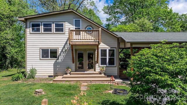 rear view of property featuring french doors, a balcony, and a yard