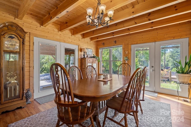 dining space with beam ceiling, light hardwood / wood-style flooring, french doors, and wooden walls