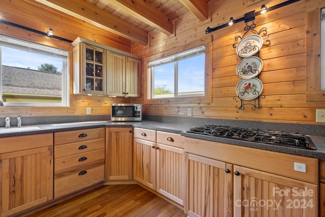 kitchen with appliances with stainless steel finishes, beamed ceiling, sink, light wood-type flooring, and wooden ceiling