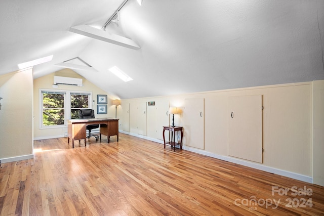 bonus room with light hardwood / wood-style floors, vaulted ceiling with skylight, and a wall mounted AC