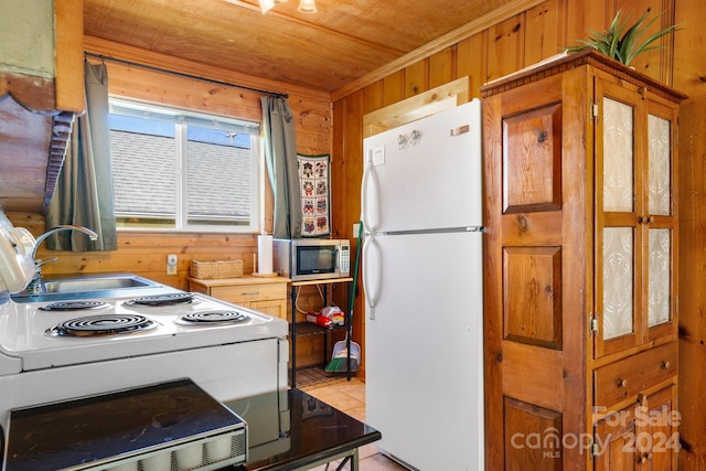 kitchen with white refrigerator, sink, wood walls, wooden ceiling, and light tile patterned floors