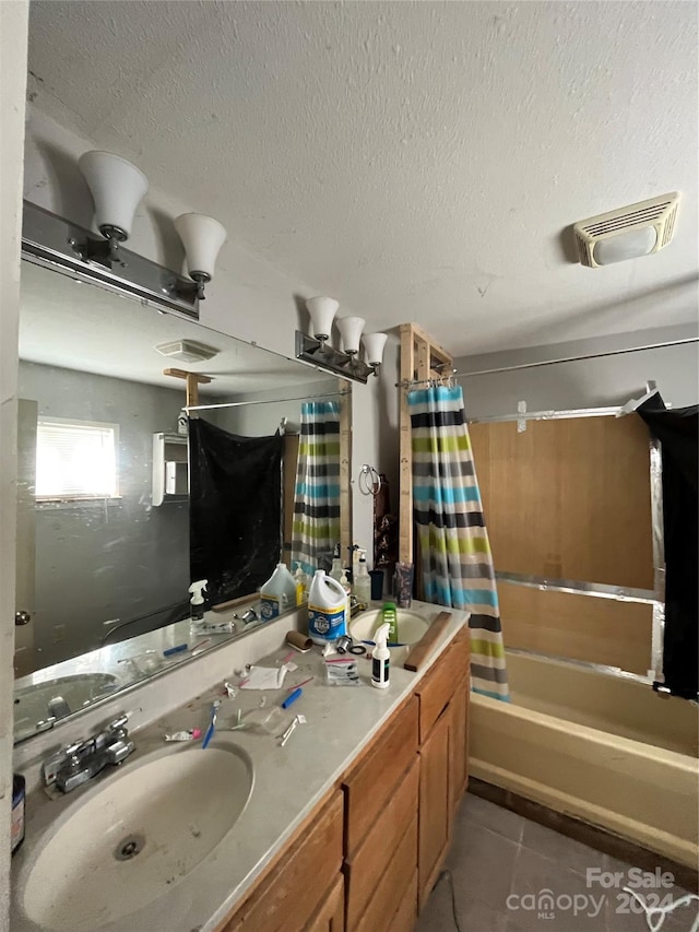 bathroom with a textured ceiling, tile flooring, oversized vanity, and shower / bath combo with shower curtain