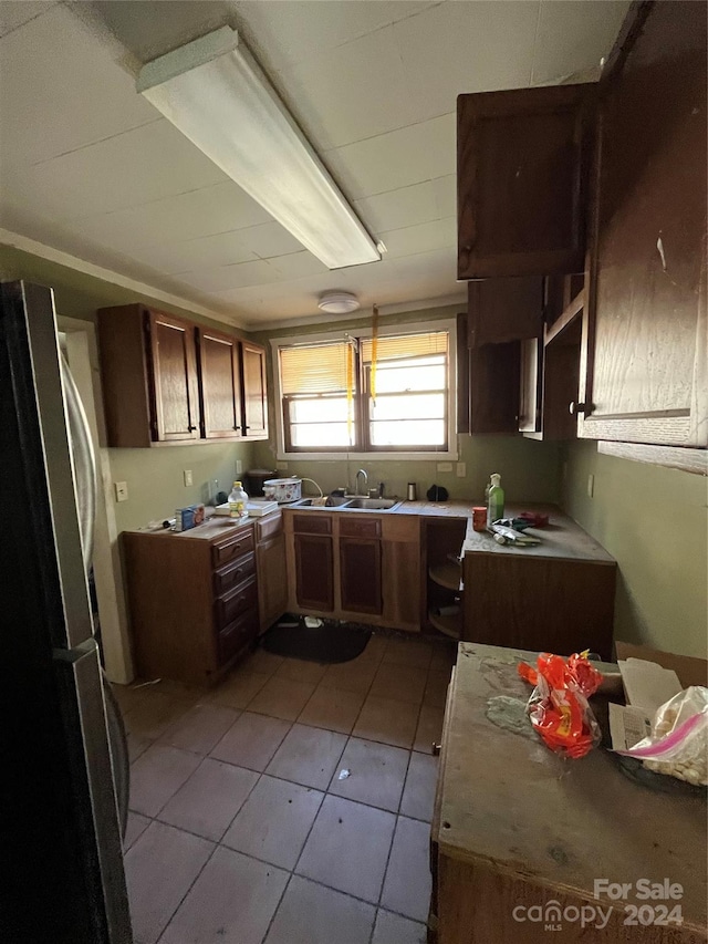 kitchen with light tile flooring, sink, and stainless steel refrigerator