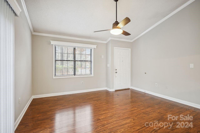 spare room with dark hardwood / wood-style floors, vaulted ceiling, ornamental molding, and ceiling fan