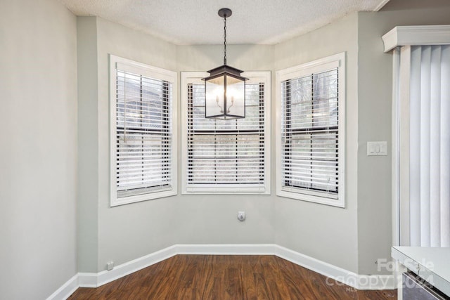 unfurnished dining area featuring plenty of natural light, dark hardwood / wood-style floors, and a textured ceiling