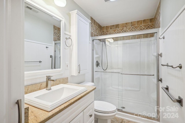 bathroom with toilet, a shower with shower door, and vanity