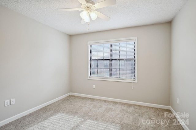 unfurnished room with a textured ceiling, ceiling fan, and light colored carpet