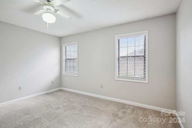 carpeted empty room featuring ceiling fan and a textured ceiling