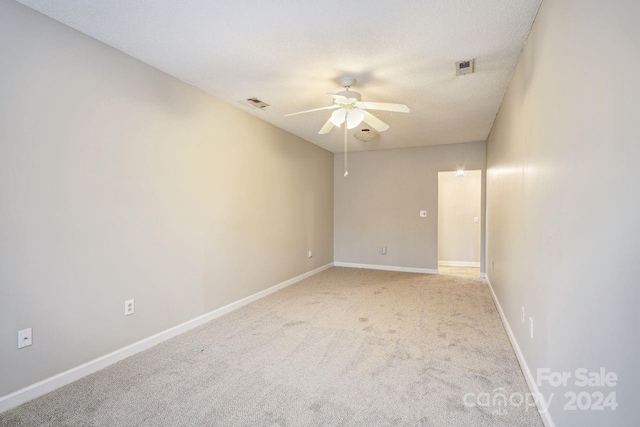 unfurnished room featuring light carpet, a textured ceiling, and ceiling fan