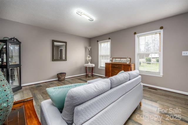 living area with a textured ceiling, baseboards, and wood finished floors