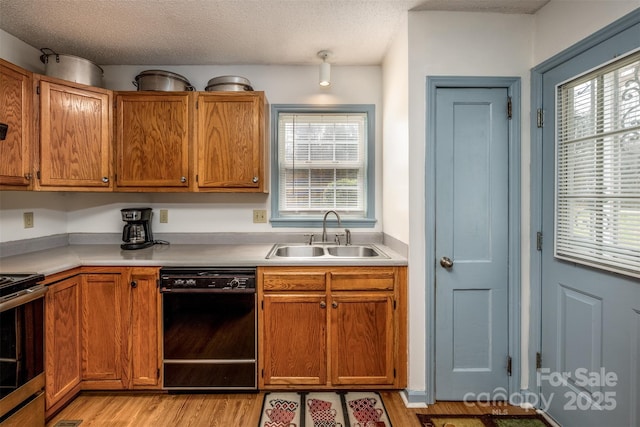 kitchen featuring a sink, black dishwasher, stainless steel range with electric stovetop, and light wood finished floors