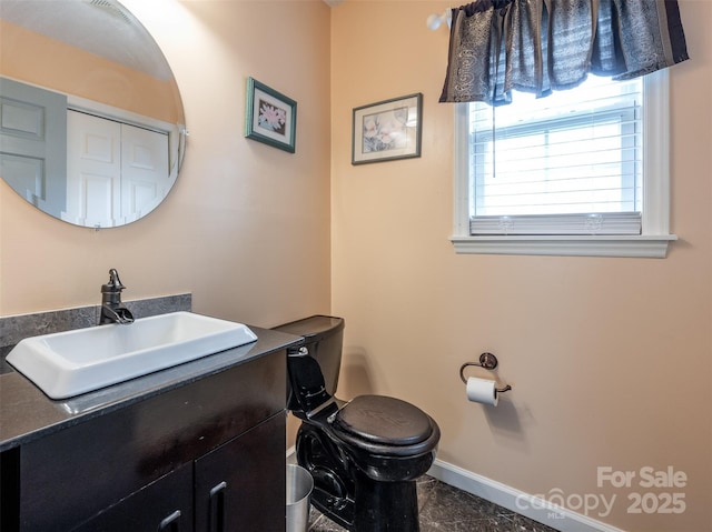 half bath with vanity, toilet, and baseboards