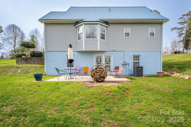 back of house with central AC unit, a lawn, metal roof, and a patio