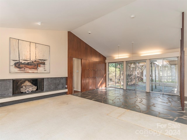 unfurnished living room featuring dark tile flooring and vaulted ceiling