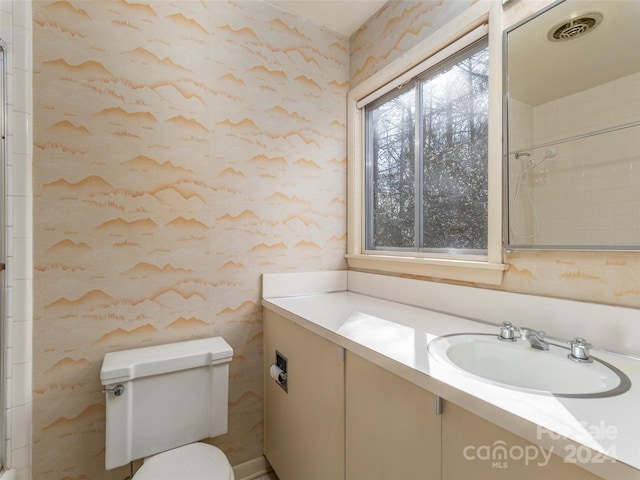 bathroom with a shower, large vanity, toilet, and tile walls