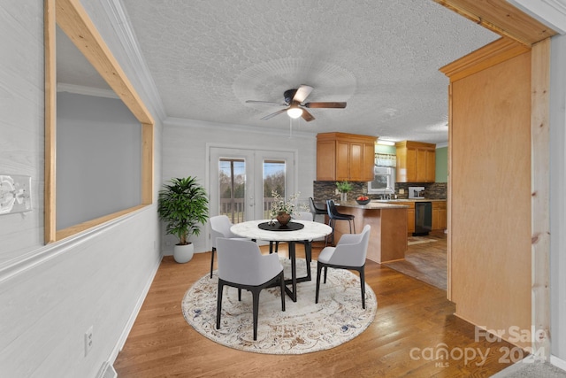 dining space with ceiling fan, light hardwood / wood-style floors, sink, crown molding, and french doors