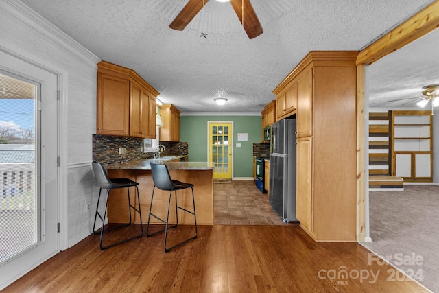 kitchen with light hardwood / wood-style floors, a kitchen bar, ceiling fan, and appliances with stainless steel finishes