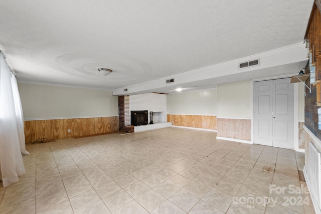 unfurnished living room with brick wall, crown molding, a textured ceiling, and a fireplace