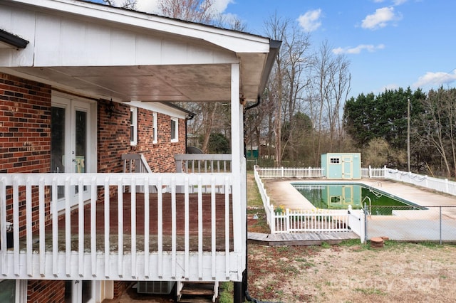 deck featuring an outdoor structure and a fenced in pool