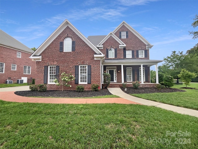 view of front of home featuring cooling unit, a front lawn, and covered porch