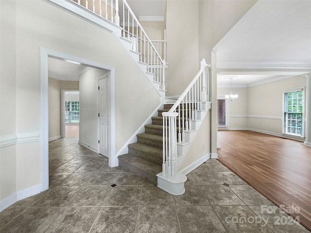 stairs featuring crown molding, wood-type flooring, a chandelier, and a high ceiling